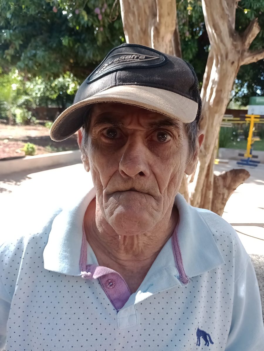 Senhor residente de boné no pátio ao ar livre sob a sombra das árvores do Asilo Pio XII