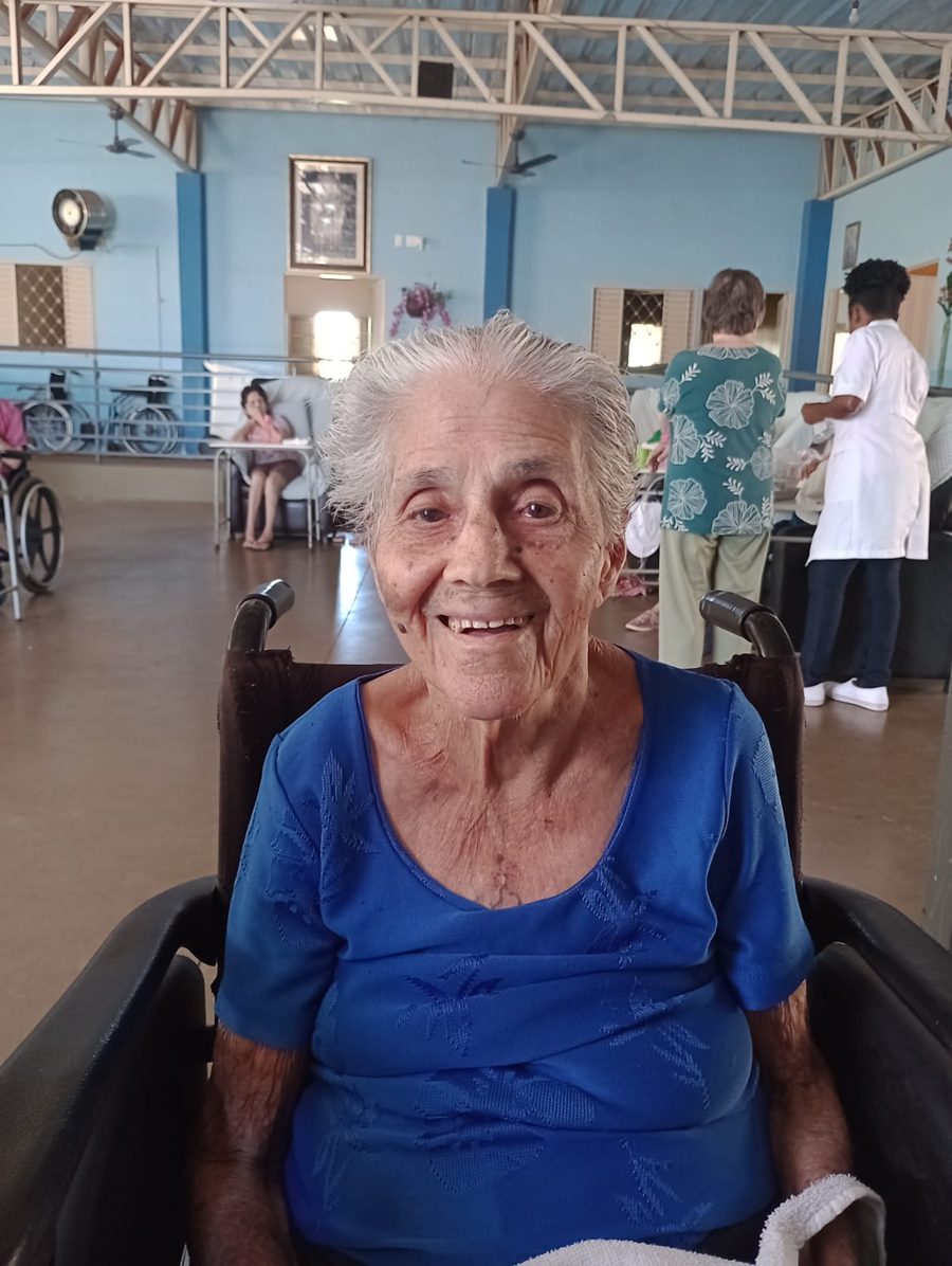 Moradora sorridente no salão de convivência do Asilo Pio XII