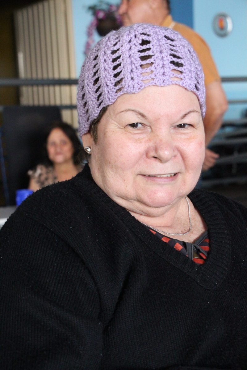 Residente com gorro de crochê lilás sorrindo em evento do asilo Pio XII